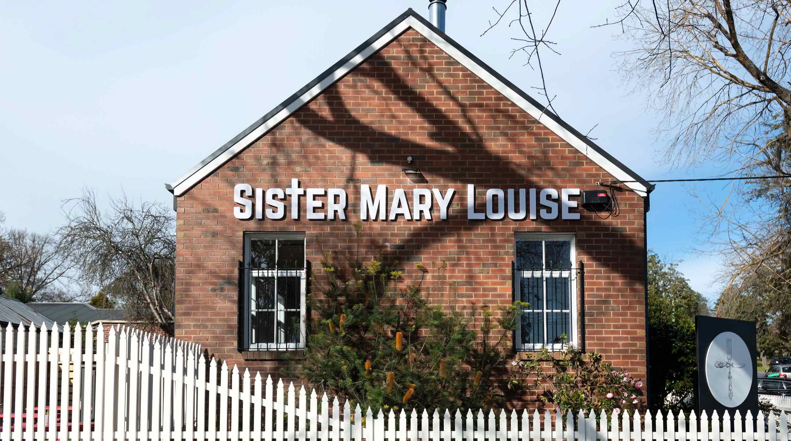 Logo of Sister Mary Louise on the red brick cafe wall.