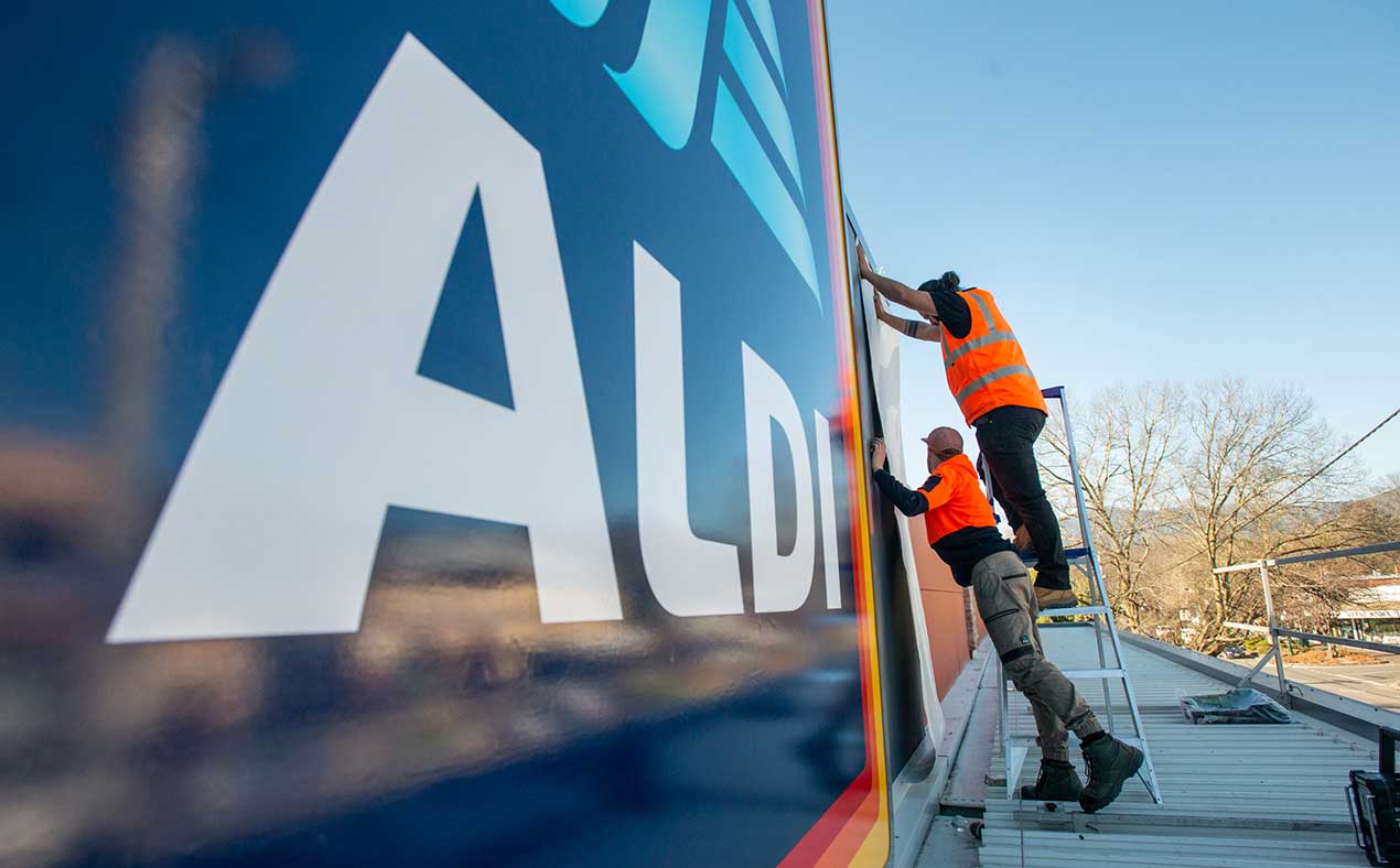Aldi branding and Paul Sonsie installing the mural they designed.
